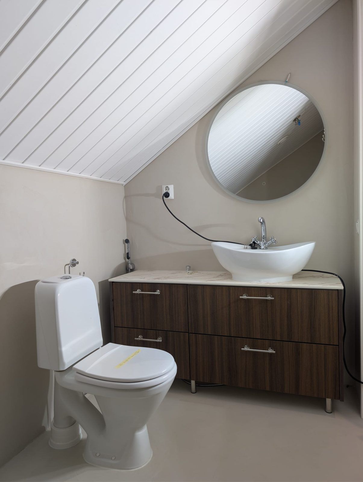 Erillis-wc mikrosementtilattialla, pähkinäkaluste ja pyöreä peili Tampereella